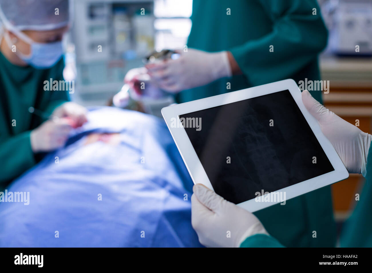 Chirurgo utilizzando tavoletta digitale mentre si sta operando il paziente nel teatro di funzionamento Foto Stock