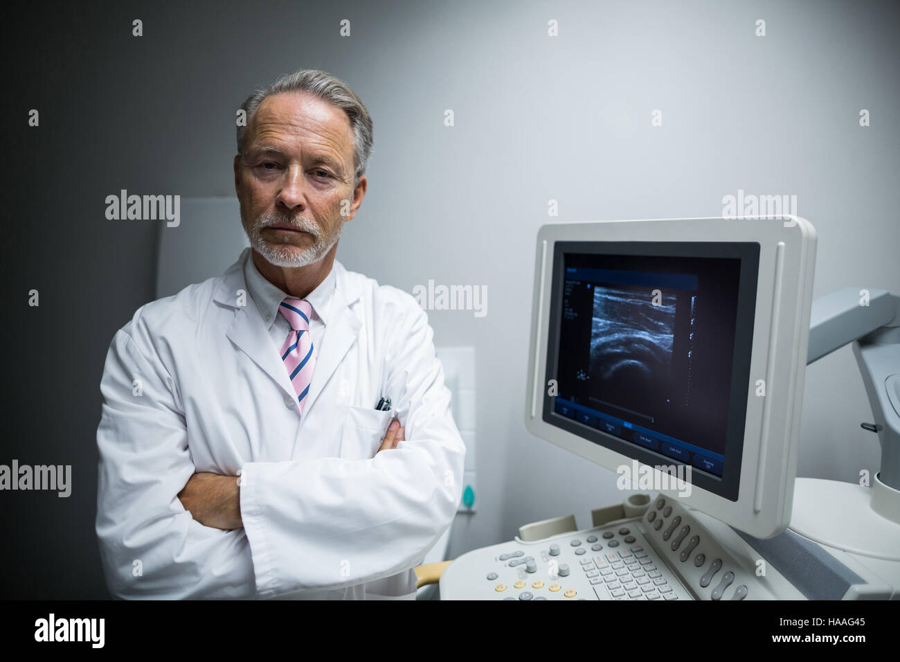 Chirurgo con le braccia incrociate in piedi vicino al dispositivo ad ultrasuoni macchina Foto Stock