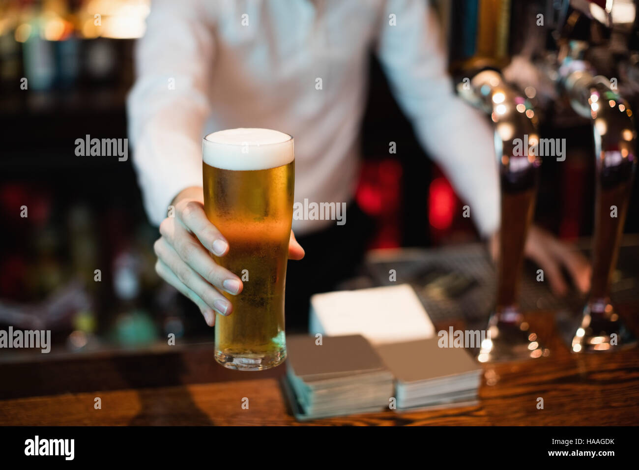 Il Barista serve un bicchiere di birra sul bancone bar Foto Stock