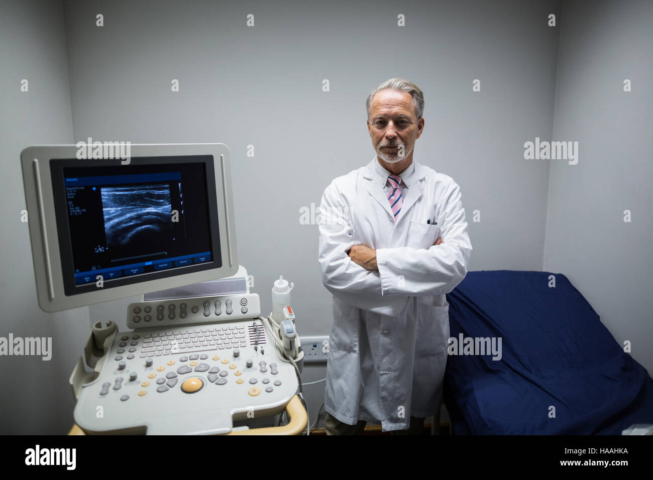 Chirurgo con le braccia incrociate in piedi vicino al dispositivo ad ultrasuoni macchina Foto Stock