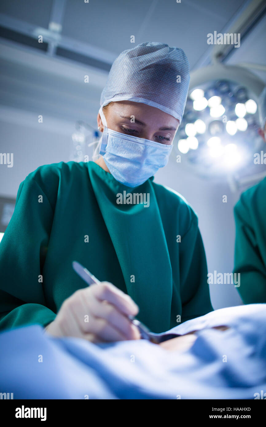 Donna chirurgo di eseguire l'operazione nel teatro di funzionamento Foto Stock