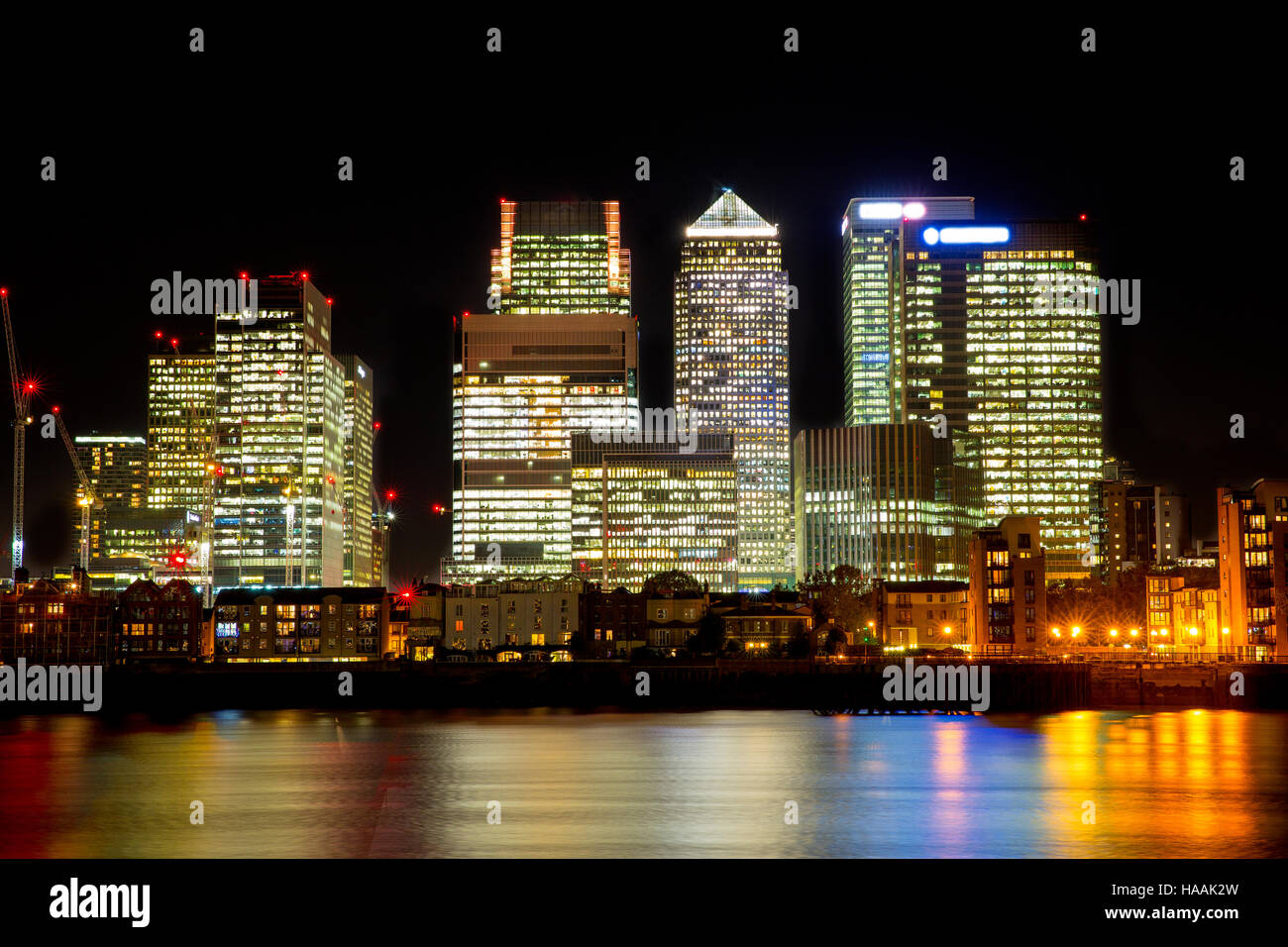 Vista notturna di Canary Wharf e il quartiere circostante e con il fiume Tamigi in primo piano. Foto Stock