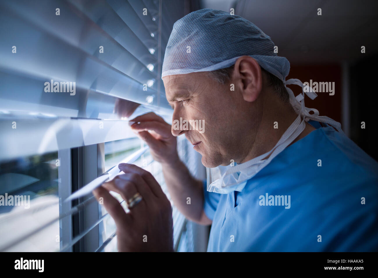 Chirurgo guardando attraverso la finestrella cieco all ospedale Foto Stock