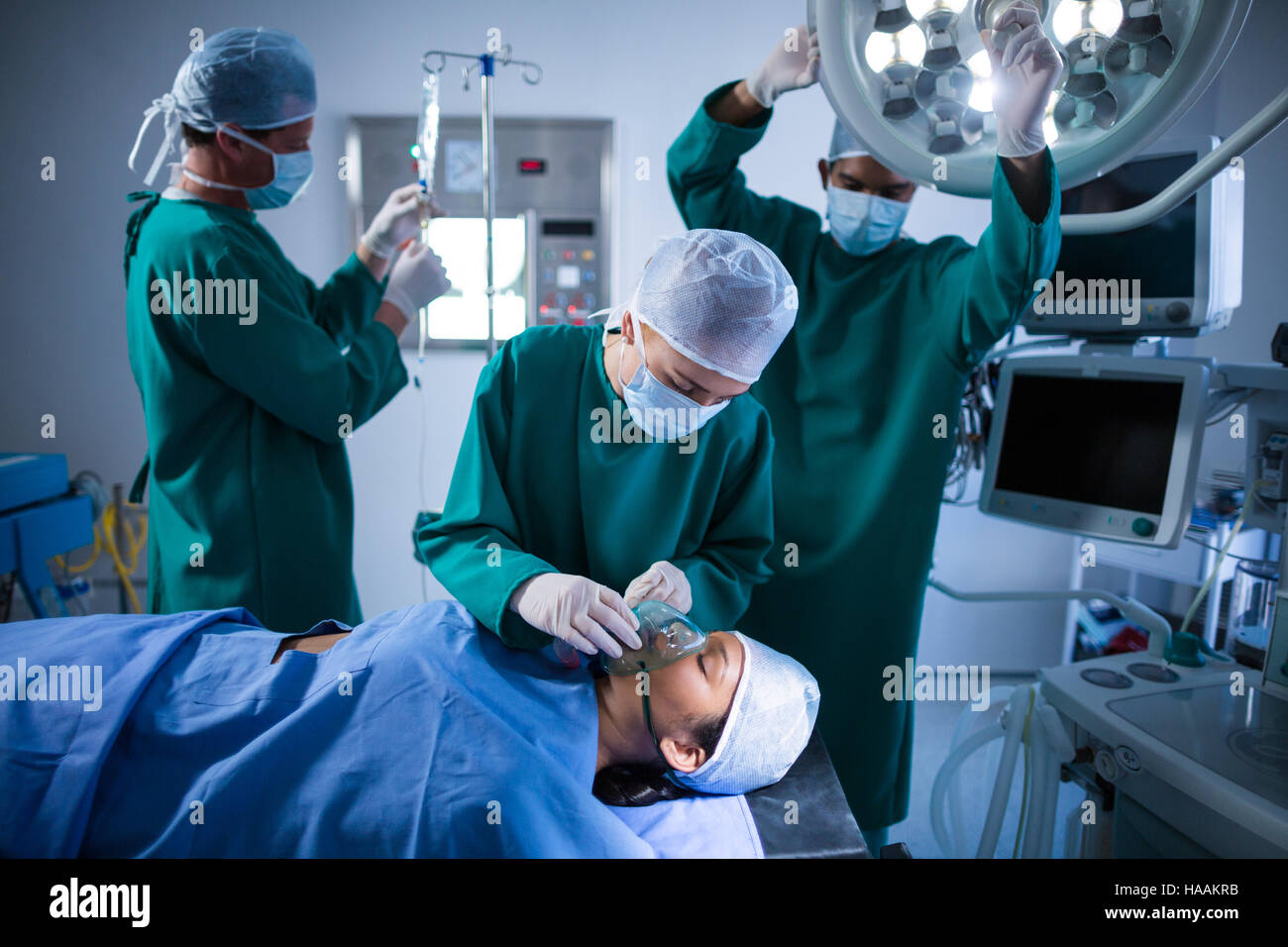 I chirurghi regolando le maschere di ossigeno sulla bocca del paziente nel teatro di funzionamento Foto Stock