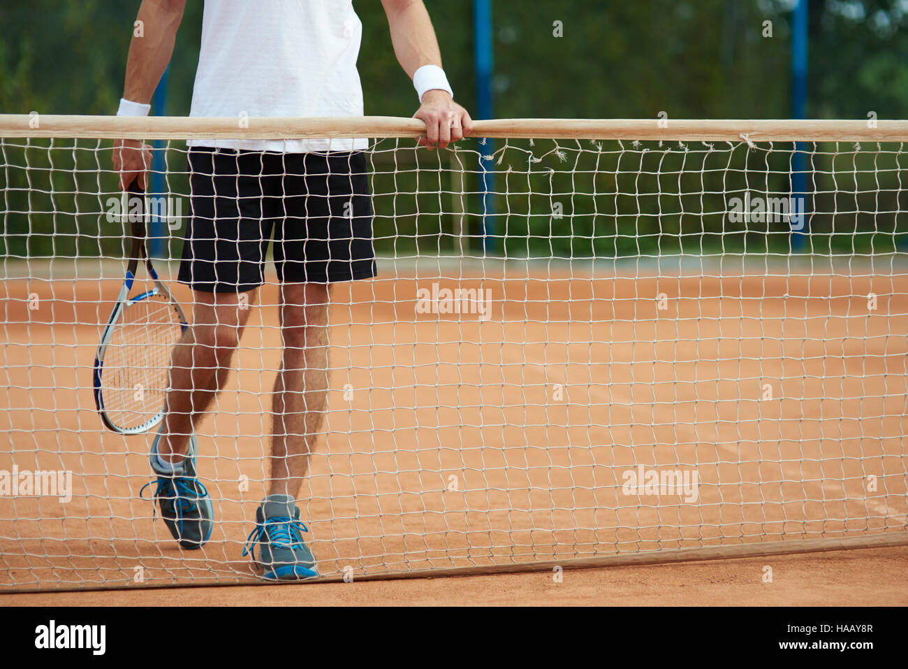 Uomo in piedi dietro un tennis net Foto Stock