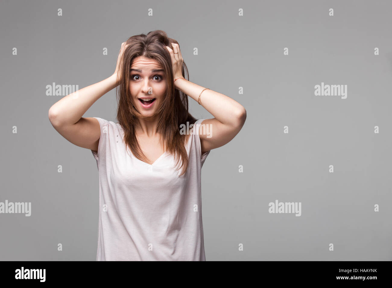 Ritratto di bella bruna donna con un espressione stupita in posa di studio su sfondo grigio Foto Stock
