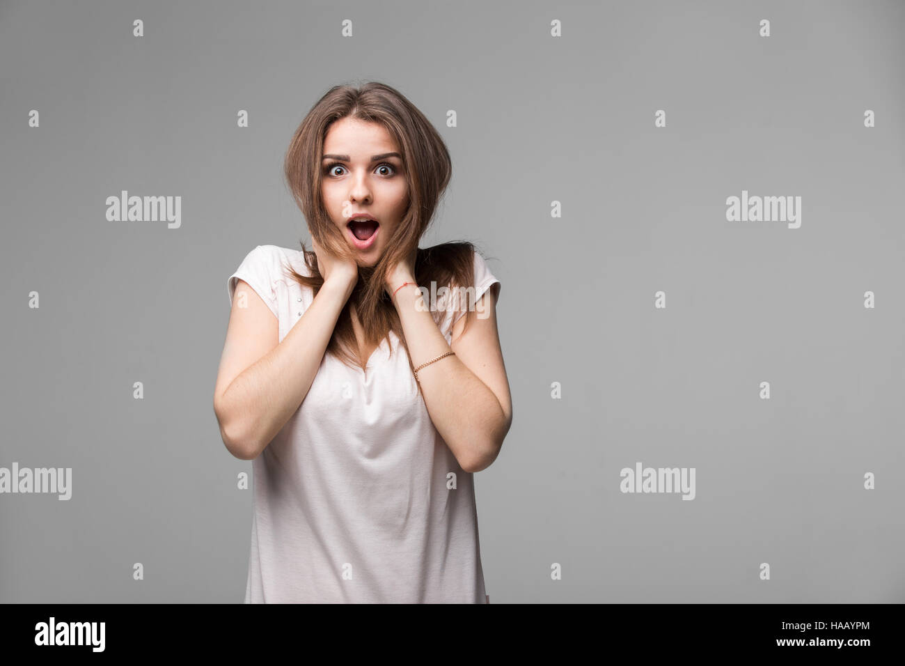 Ritratto di bella bruna donna con un espressione stupita in posa di studio su sfondo grigio Foto Stock