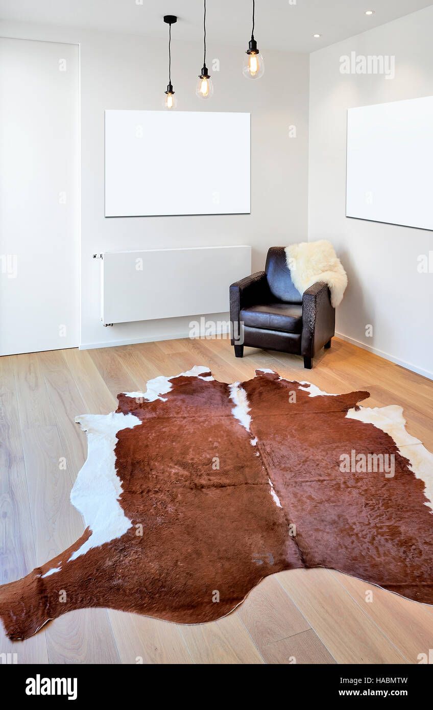 Tappeto di mucca e poltrona sul nuovo pavimento in legno in un appartamento  di lusso Foto stock - Alamy