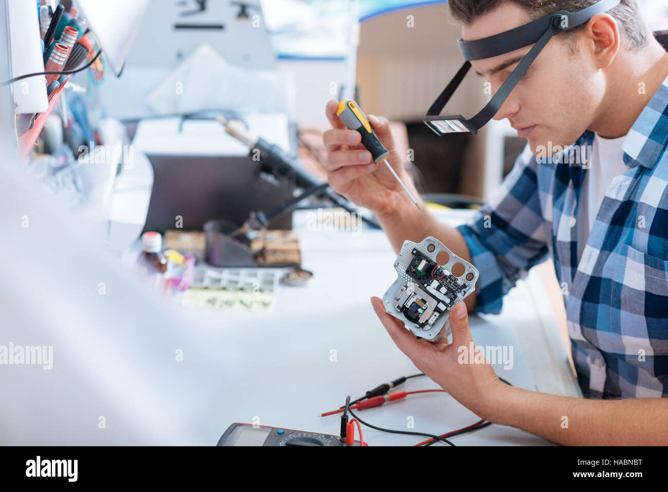 Giovane uomo che ripara fuchi chip con un cacciavite Foto Stock