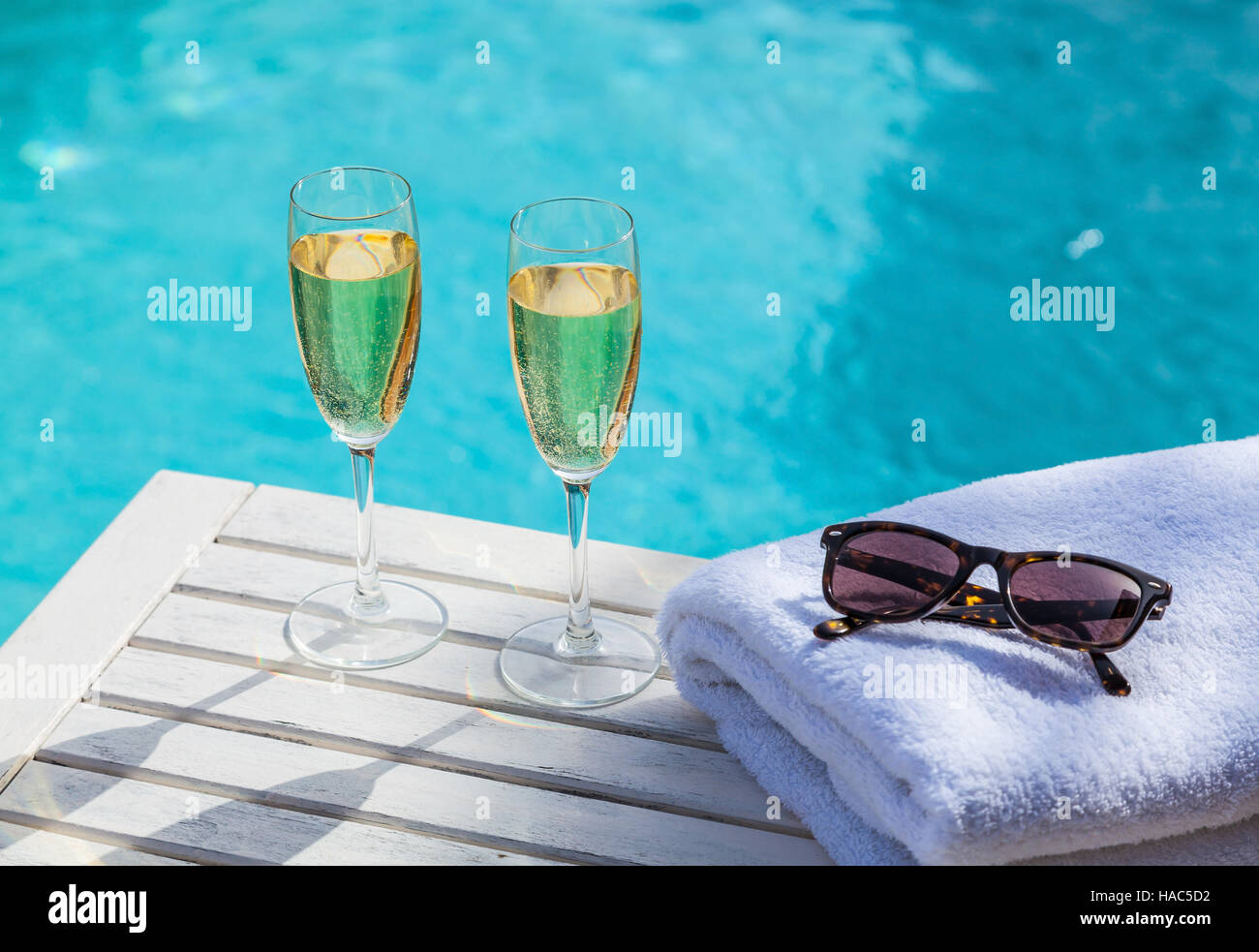 Due bicchieri di champagne su un bianco tavolo di legno accanto alla piscina in estate. Foto Stock