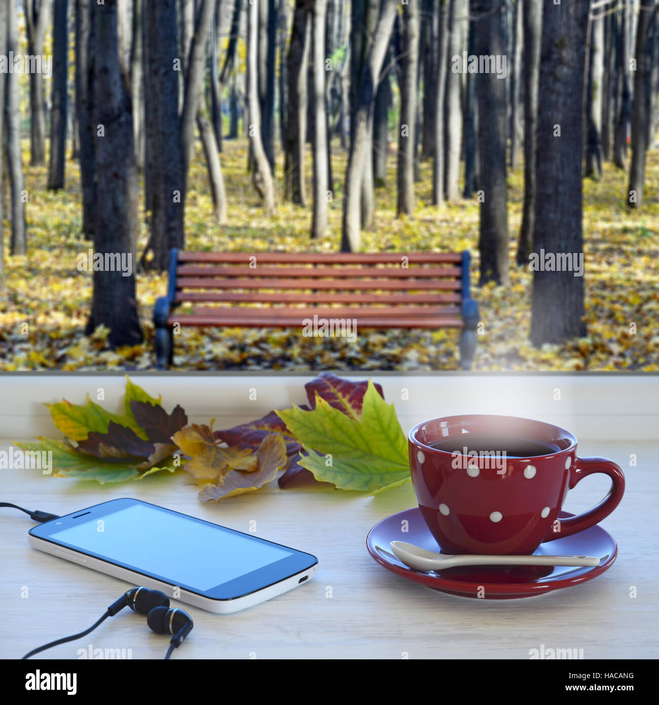 Tazza di caffè, lo smartphone, le cuffie e le foglie di autunno su un  davanzale. Nella finestra di sfondo con paesaggio autunnale Foto stock -  Alamy
