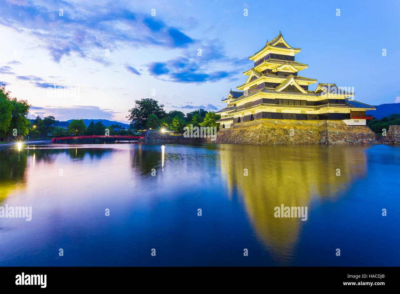 Il Castello Matsumoto splendidamente illuminata di notte blu ora con esposizione lunga riflessione nel fossato acqua in Giappone Foto Stock
