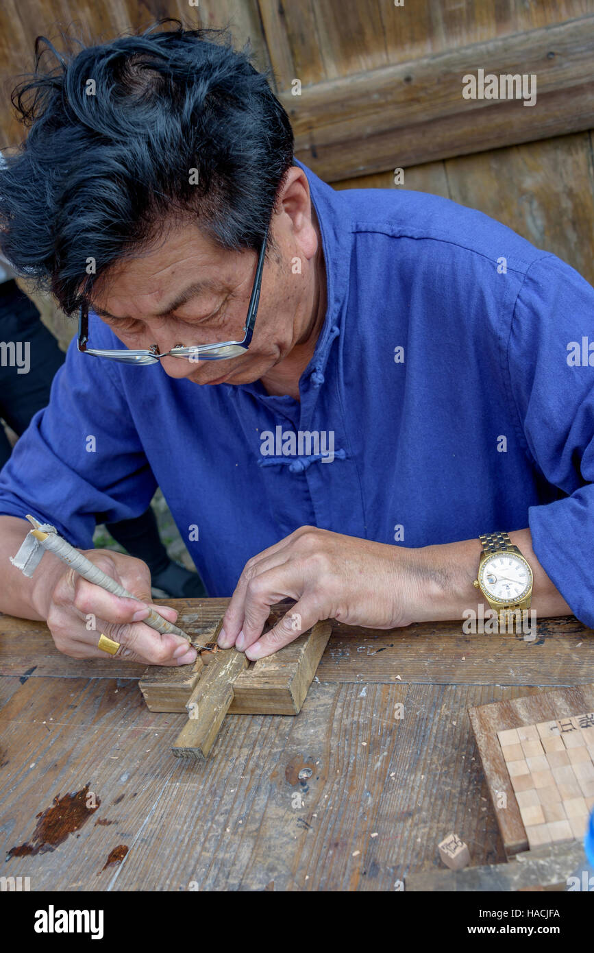 Un maestro addestrato nell'arte cinese di tipo mobile scolpisce la stampa di caratteri in legno a Dongyuan village, Ruian, Cina. Foto Stock