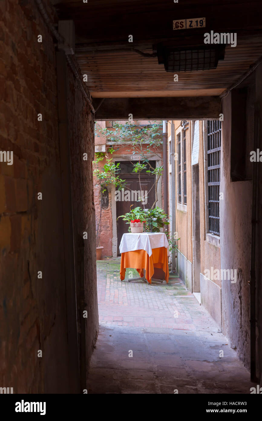 Allyway scuro con un invitante cortile, Venezia, Italia. Foto Stock