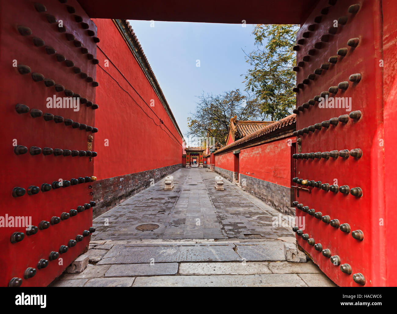 Rosso di legno antico porta massicce porte di bronzo con le manopole in imperatori cinesi città proibita per separare le sezioni residenziale da parte dei visitatori. Foto Stock