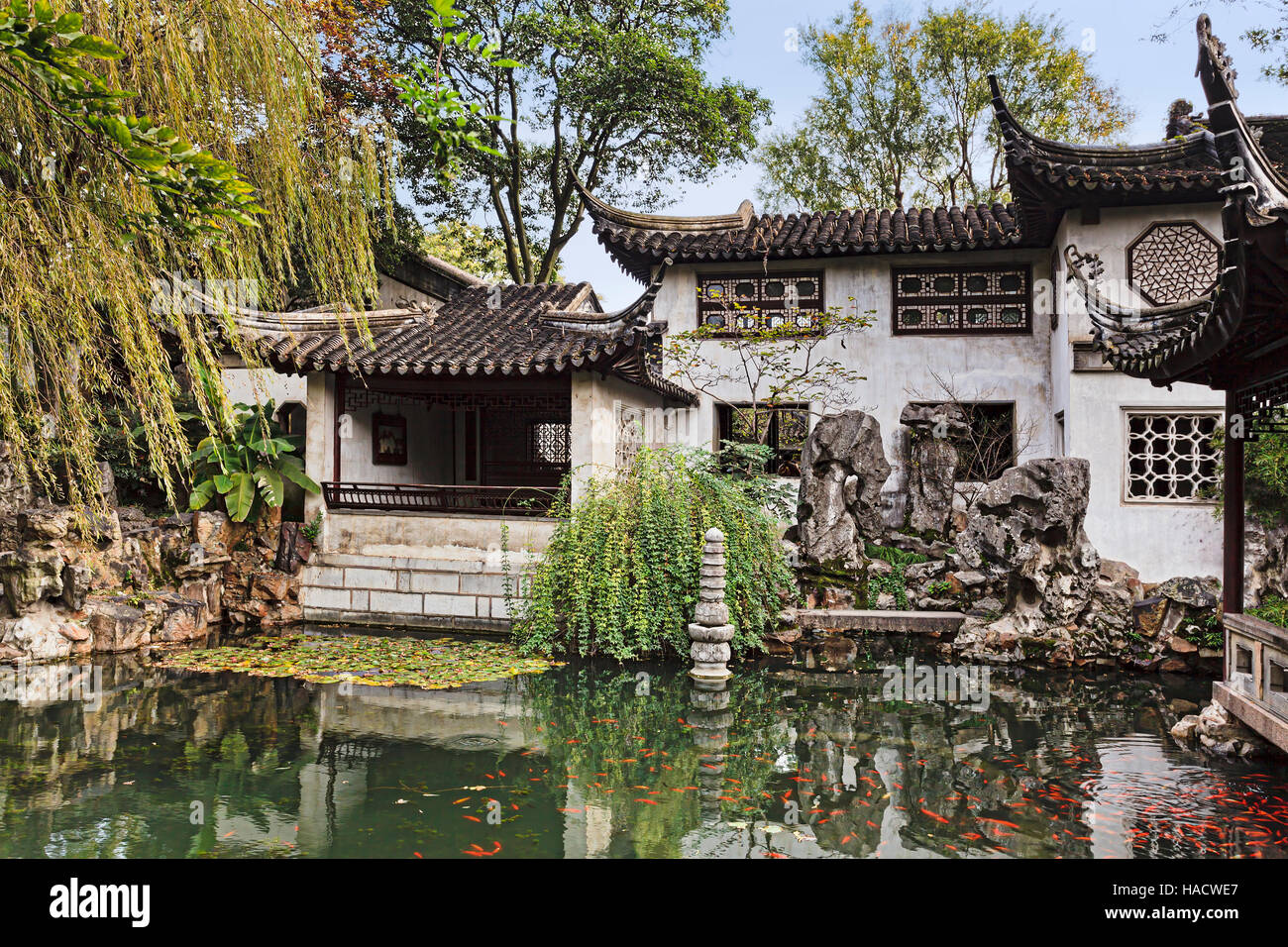 Formale cinese tradizionale giardino con padiglioni storici e tetti che riflette ancora in acque di stagno con red carp pesci. Foto Stock