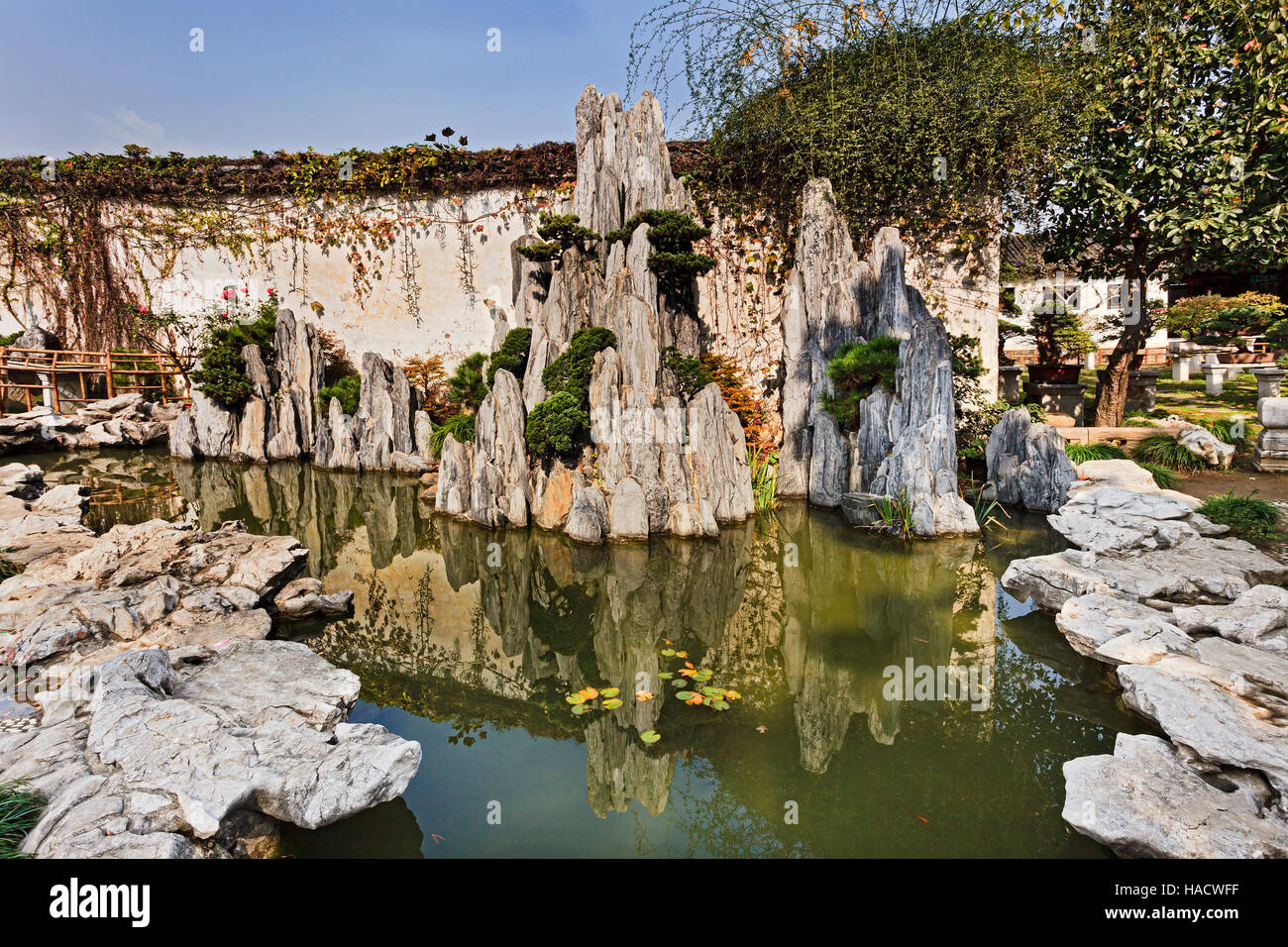 Mini formazione di roccia da ancora stagno di acqua in un giardino pubblico di Suzhou City in Cina su un luminoso giorno d'autunno. Foto Stock