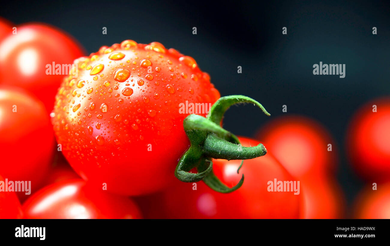 I pomodori. Pomodori ciliegini. Cocktail di pomodori. Mosti di uve fresche pomodoro su sfondo nero Foto Stock