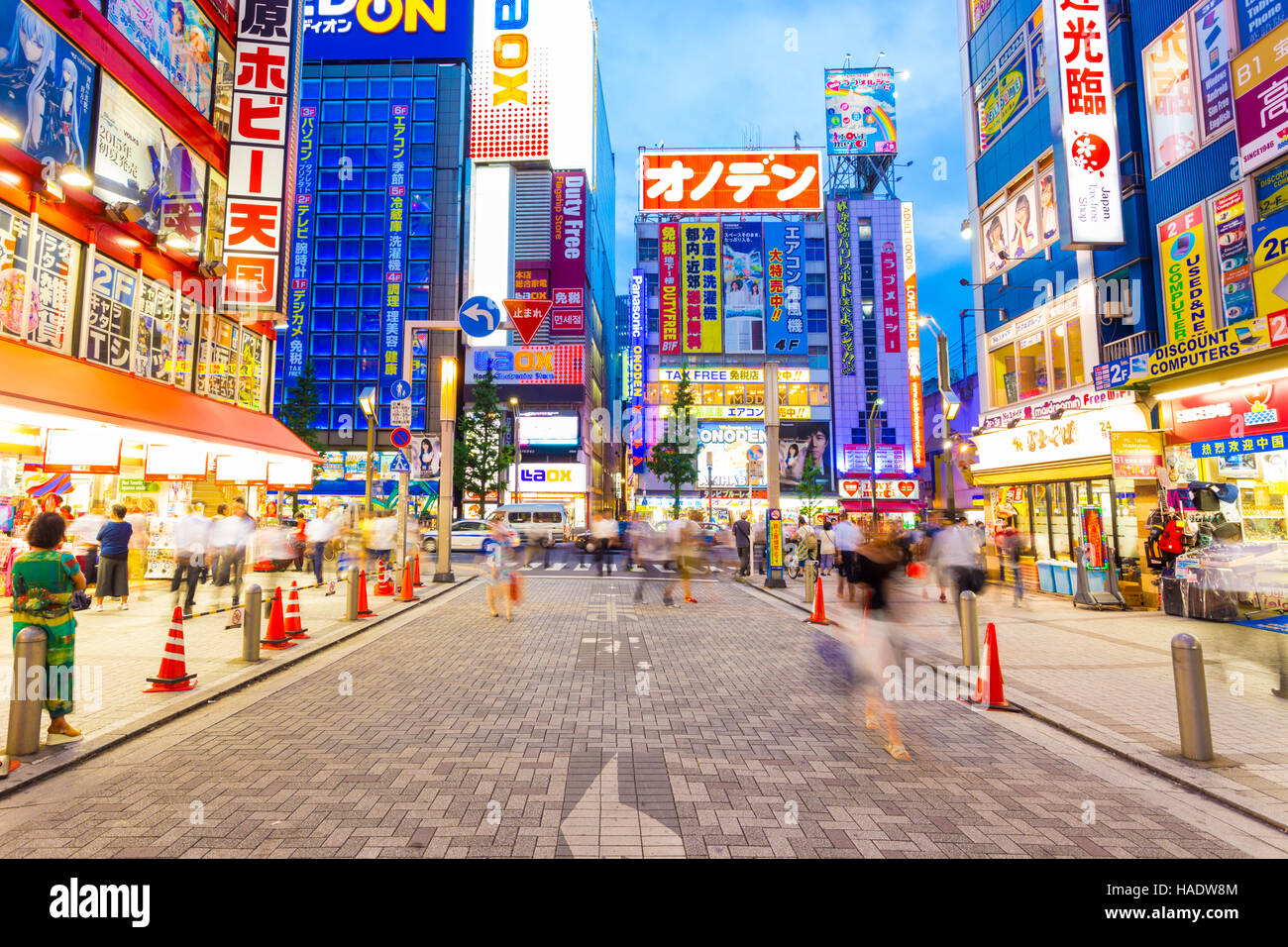 Le persone occupate a piedi attorno al centro del mozzo di elettronica quartiere di Akihabara tra luci al neon e insegne luminose Foto Stock
