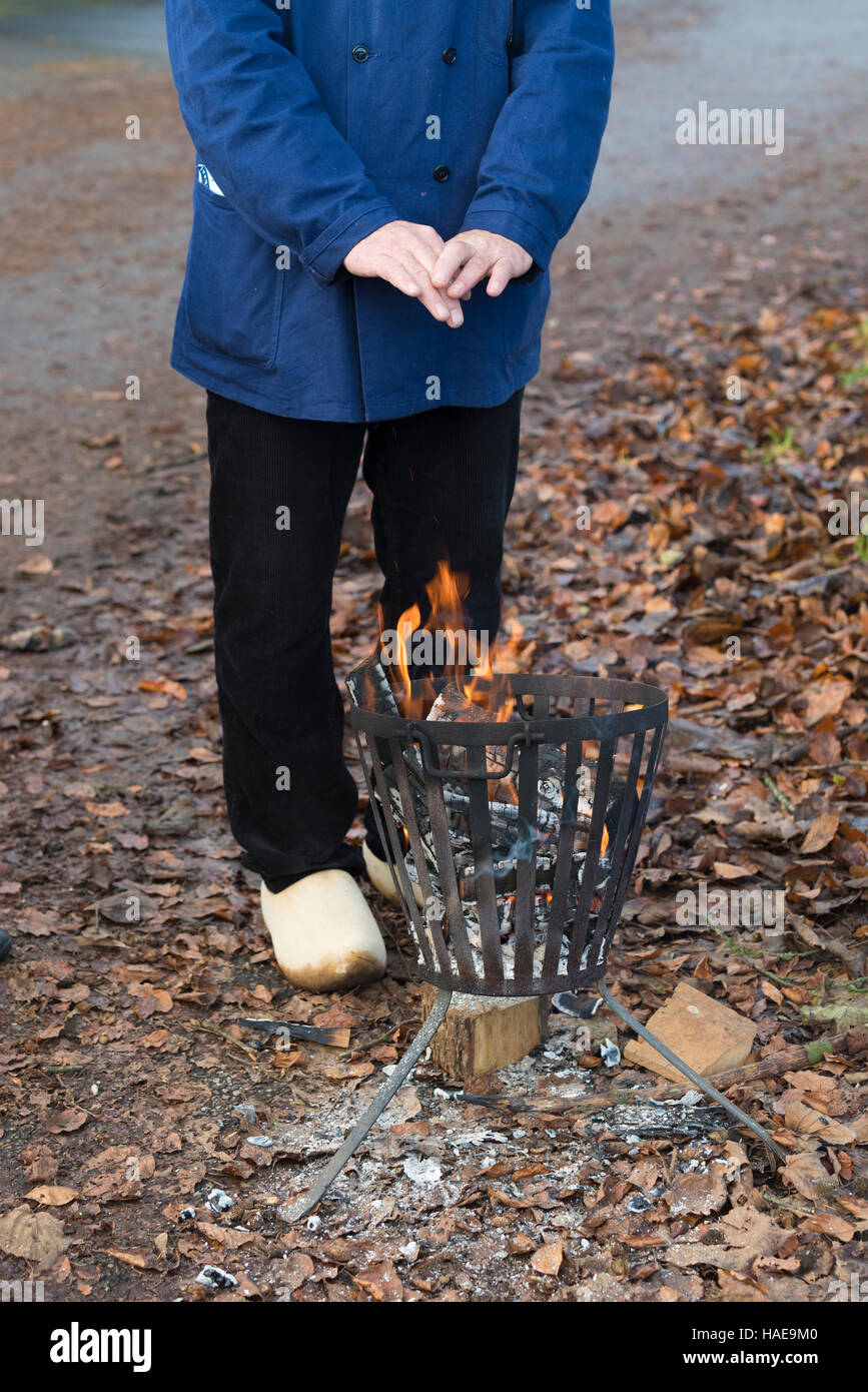 Persona riscaldando le mani su un metallo una buca per il fuoco Foto Stock