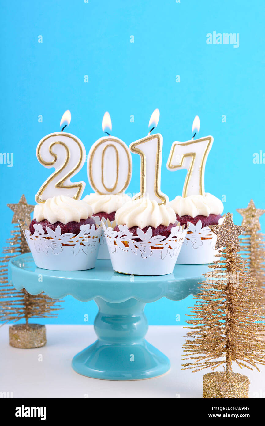 Felice Anno Nuovo tortine con 2017 candele in blu, oro e bianco inverno impostazione tema sfondo, su cakestand con oro di alberi di Natale Foto Stock