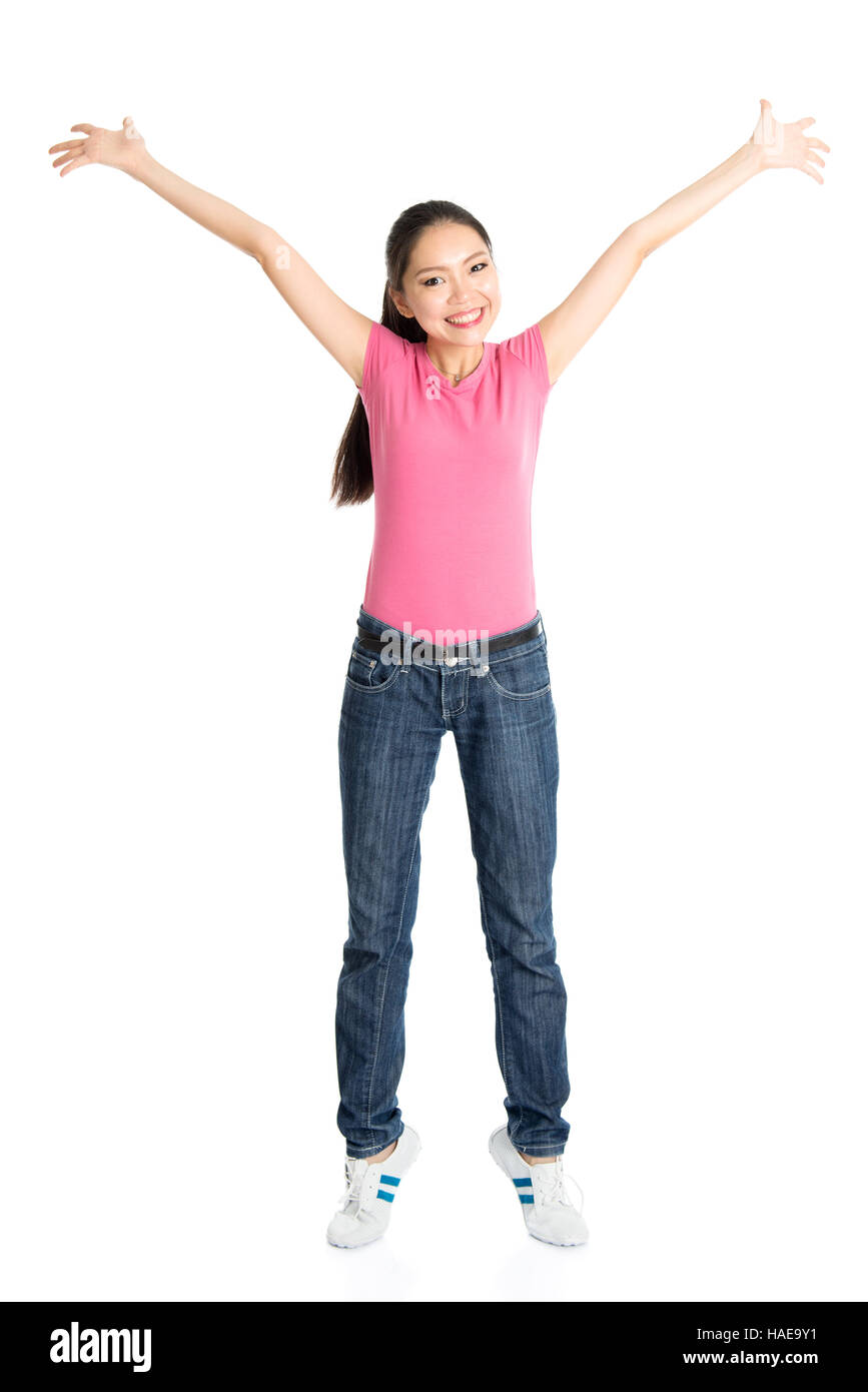 Ritratto di giovane ragazza asiatica in maglia rosa e jeans braccia tese, corpo pieno in piedi isolato su sfondo bianco. Foto Stock