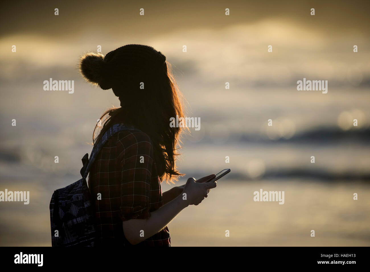 Una ragazza che indossa un cappello di lana sms sul suo telefono cellulare. Foto Stock
