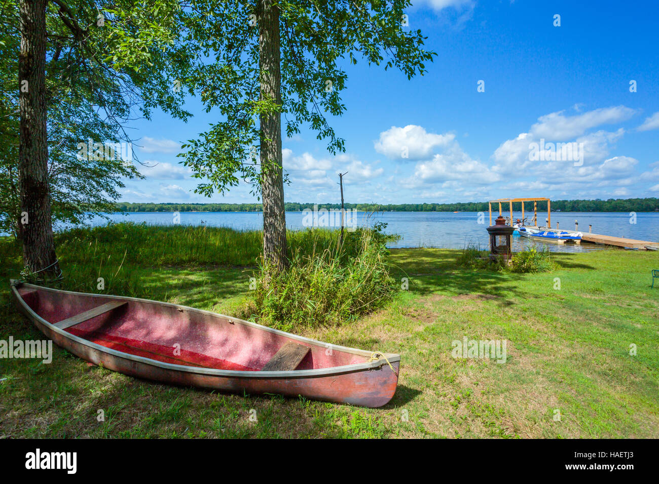 Red Canoe sulla spiaggia del lago. Foto Stock