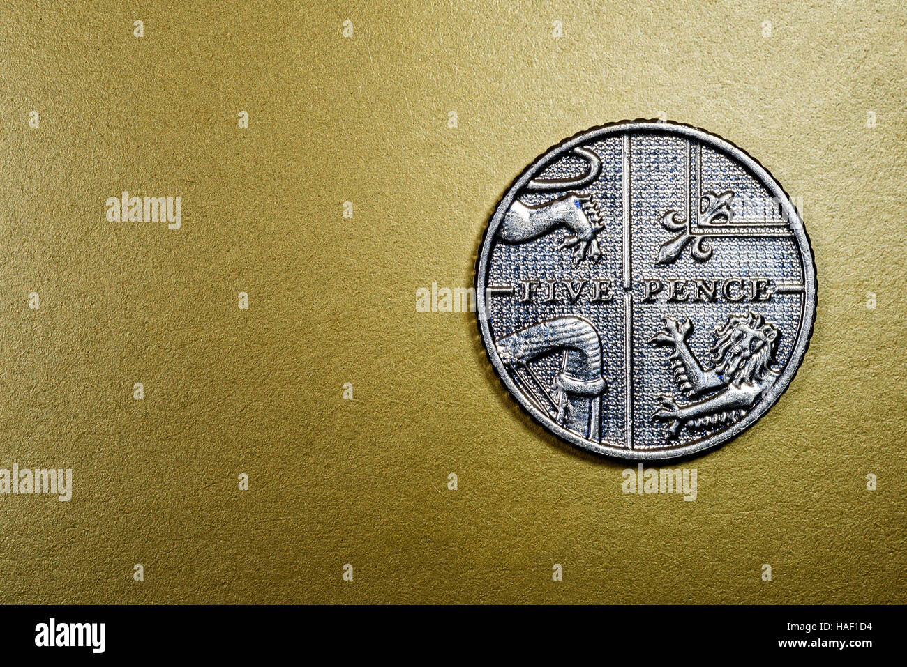 Cinque pence valuta inglese moneta in una macro close-up su un lussuoso ricco sfondo dorato. Area copyspace di finanziamento per il settore bancario, e modelli di economia Foto Stock