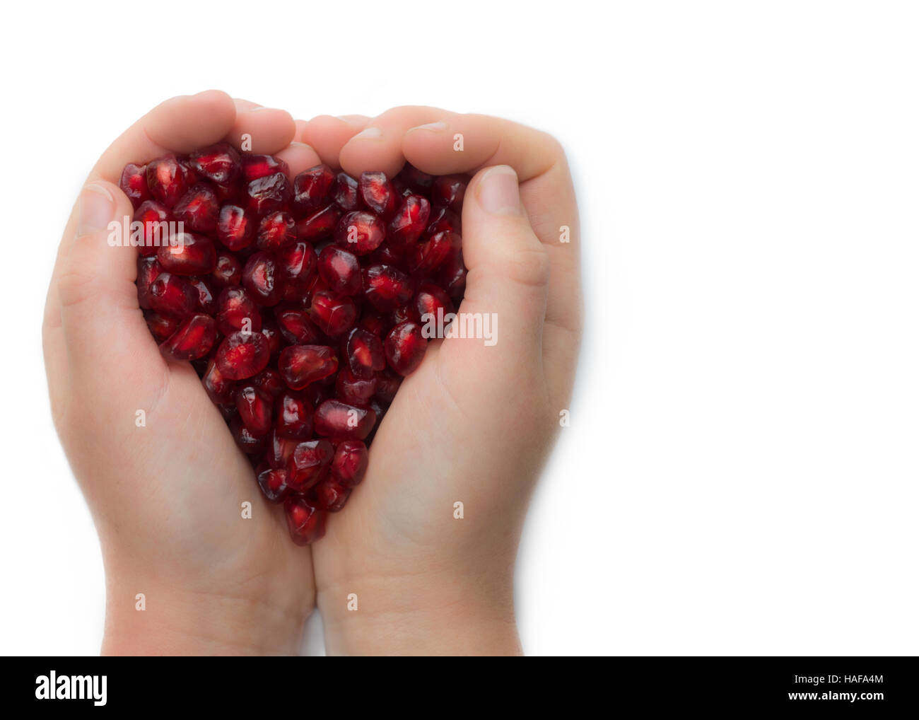 Le mani del bambino ragazzo o ragazza con frutta e colorati di rosso i semi di melograno, girato su sfondo bianco . isolato per copiare lo spazio . Foto Stock