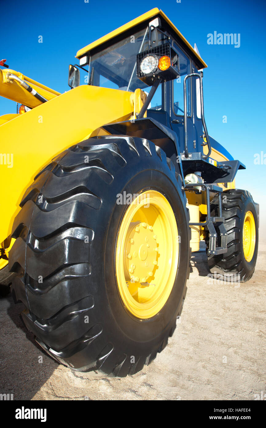 Di colore giallo brillante il trattore su uno sfondo di cielo blu in una giornata di sole Foto Stock