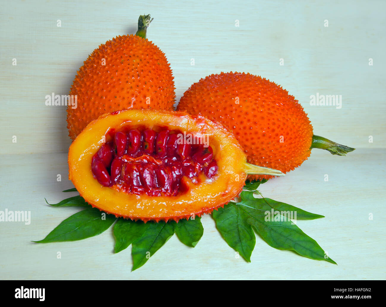 Gac frutto su legno (denominata anche come Baby Jackfruit, amaro spinoso GAC, gourd Amaro, dolce terra, melone rosso, Cochinchin Goud, Momordica cochinchinensis, Foto Stock