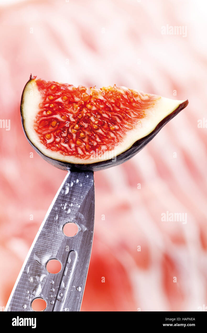 Figg (Ficus carica), frutta fresca su un punto di coltello sopra il prosciutto crudo Foto Stock