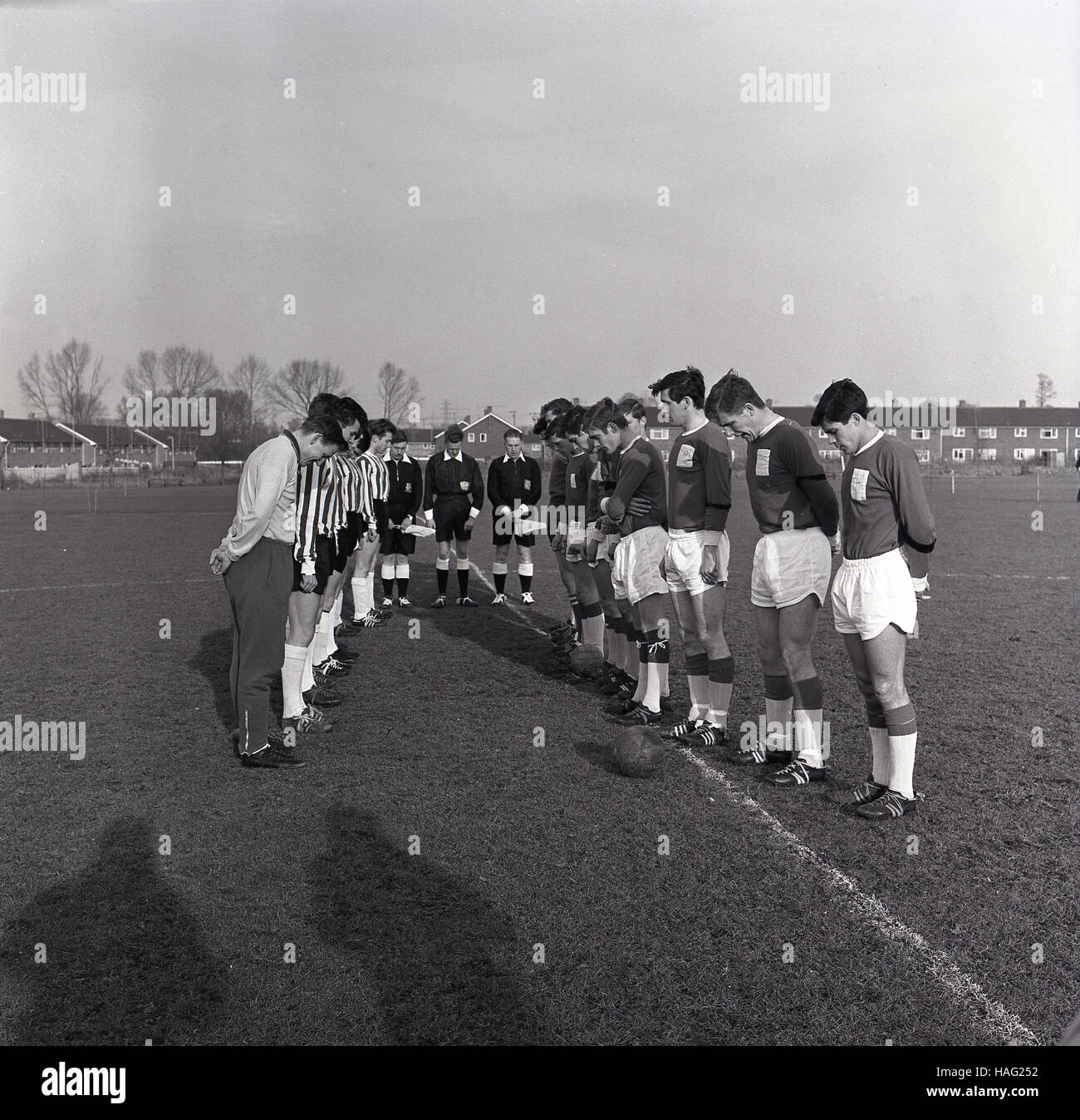 1965, storico, due di calcio amatoriale squadre stand di fronte a ogni altro sul passo, con la loro testa inchinata per osservare due minuti di silenzio prima che il gioco sul ricordo domenica, come un segno di rispetto e in onore di quei coraggiosi menwho hanno combattuto e sono morti in WW1. Foto Stock