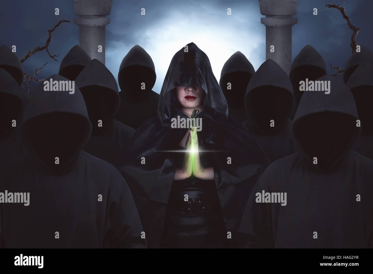 Una bella asiatica streghe pregando nella foresta di notte, in piedi con alcune persone con felpa con cappuccio nero Foto Stock