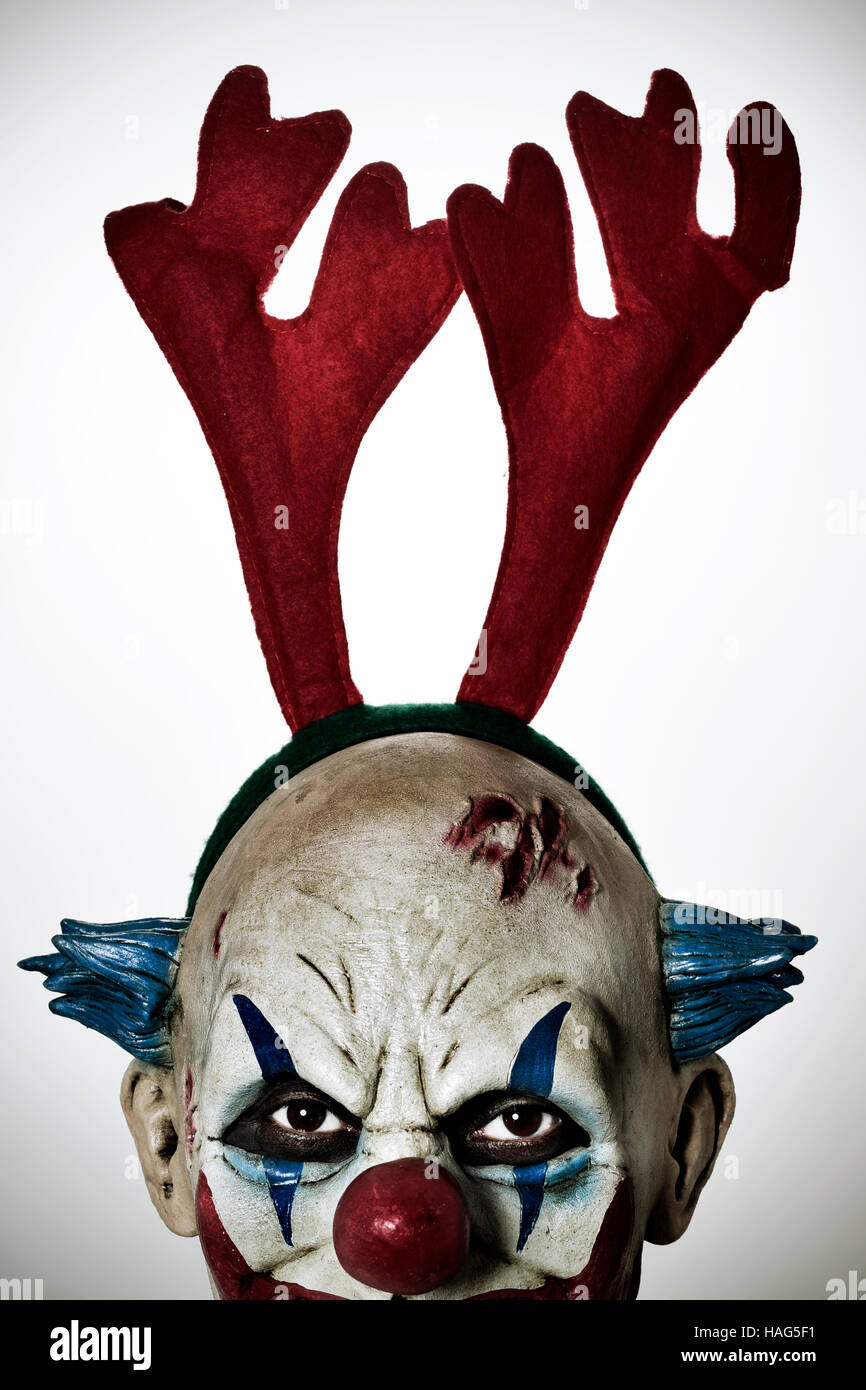 Primo piano di una paura male clown che indossa una renna palchi con archetto fissando l'osservatore Foto Stock