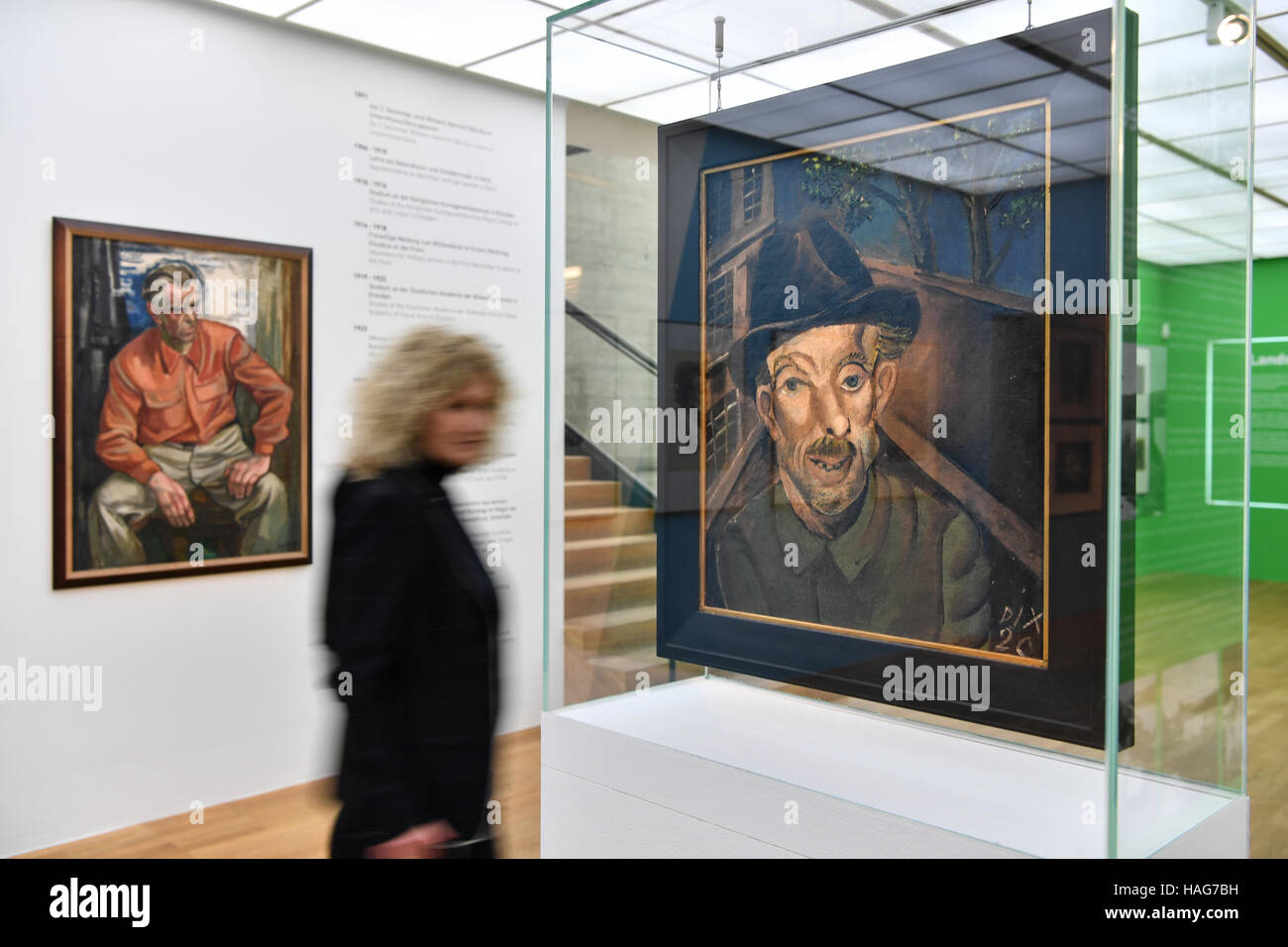 Un curatore della mostra oltrepassando la illustrazione "disoccupati" (1920) di Otto Dix al Museo Zeppelin a Friedrichshafen, Germania, 29 novembre 2016. In fondo è un ritratto di Dix dall artista Ernst Bursche. La mostra Alles muss ich sehen! A Zeppelin Museum commemora il 125th compleanno di Otto Dix e corre dal 02.12.2016 - 17.04.2017. Foto: Felix Kästle/dpa Foto Stock