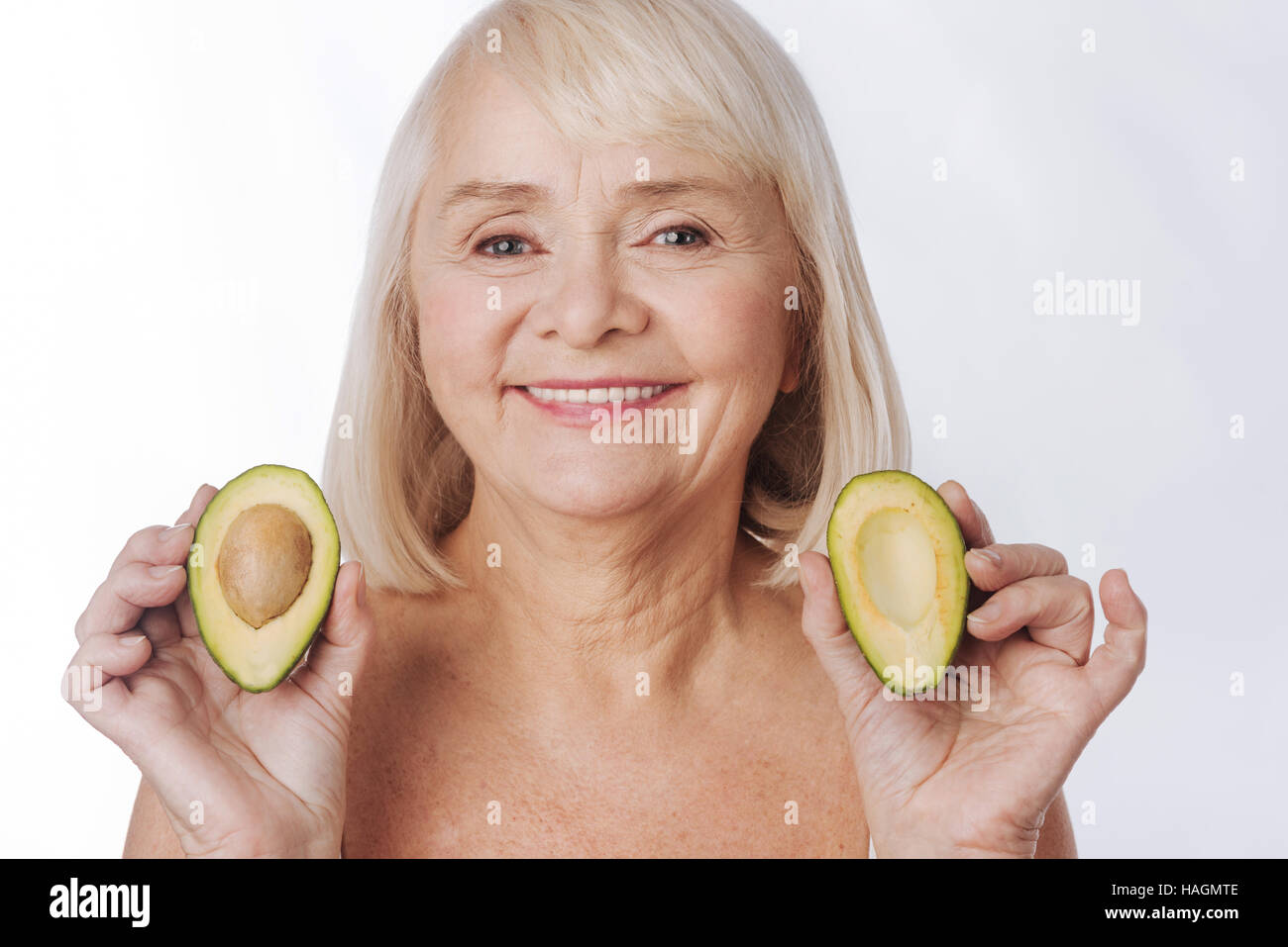 Piacevole donna affascinante avente due metà di avocado nelle sue mani Foto Stock