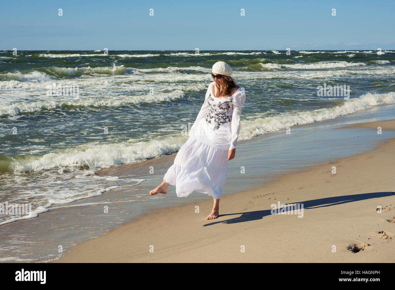 Donna in abito bianco dancing vicino al mare Foto Stock
