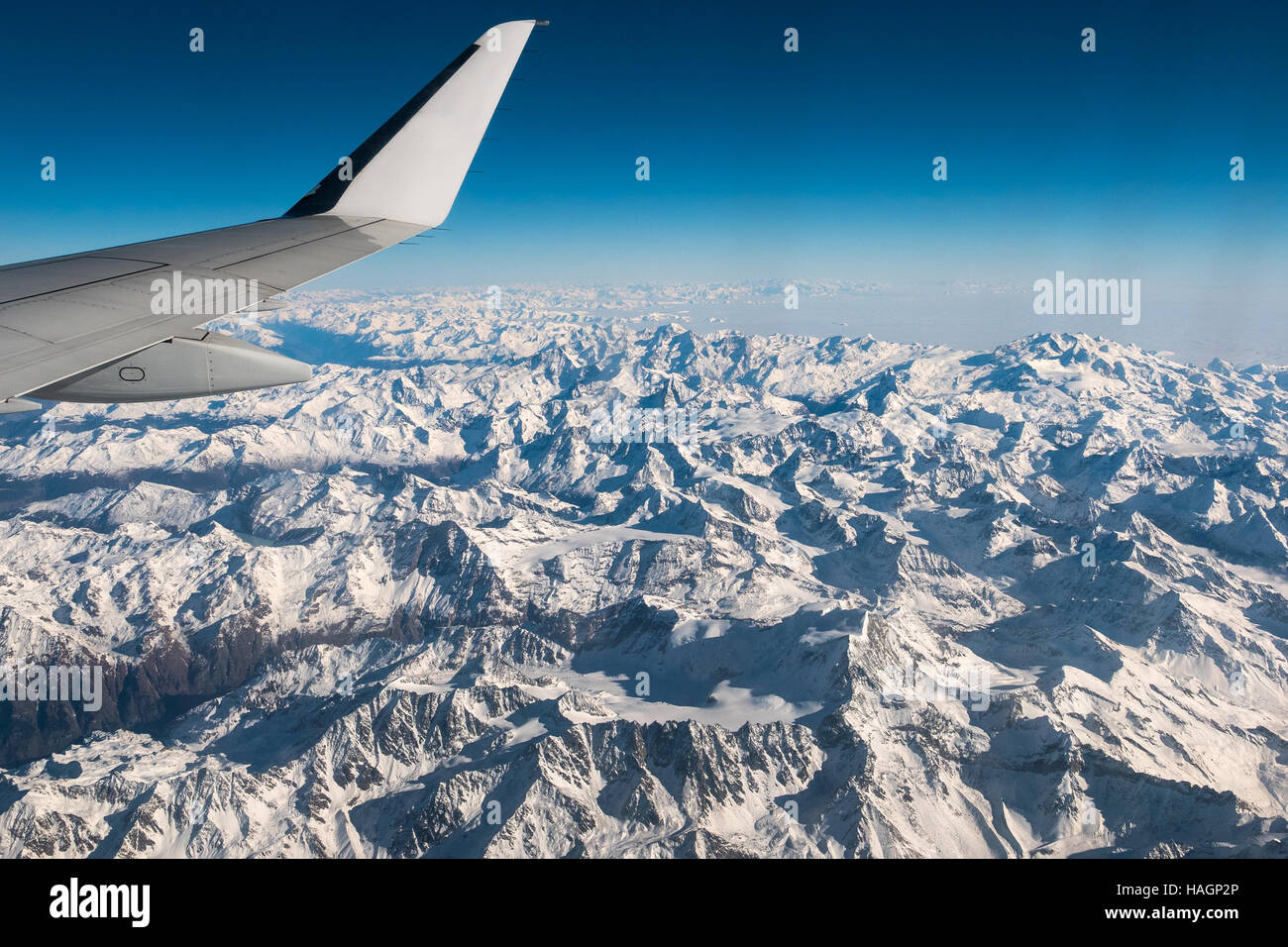 Vista aerea della Svizzera Italiana Alpi in inverno, con aereo generico di ala. Cime montagne e ghiacciai. Vista espansiva, cielo blu chiaro. Foto Stock