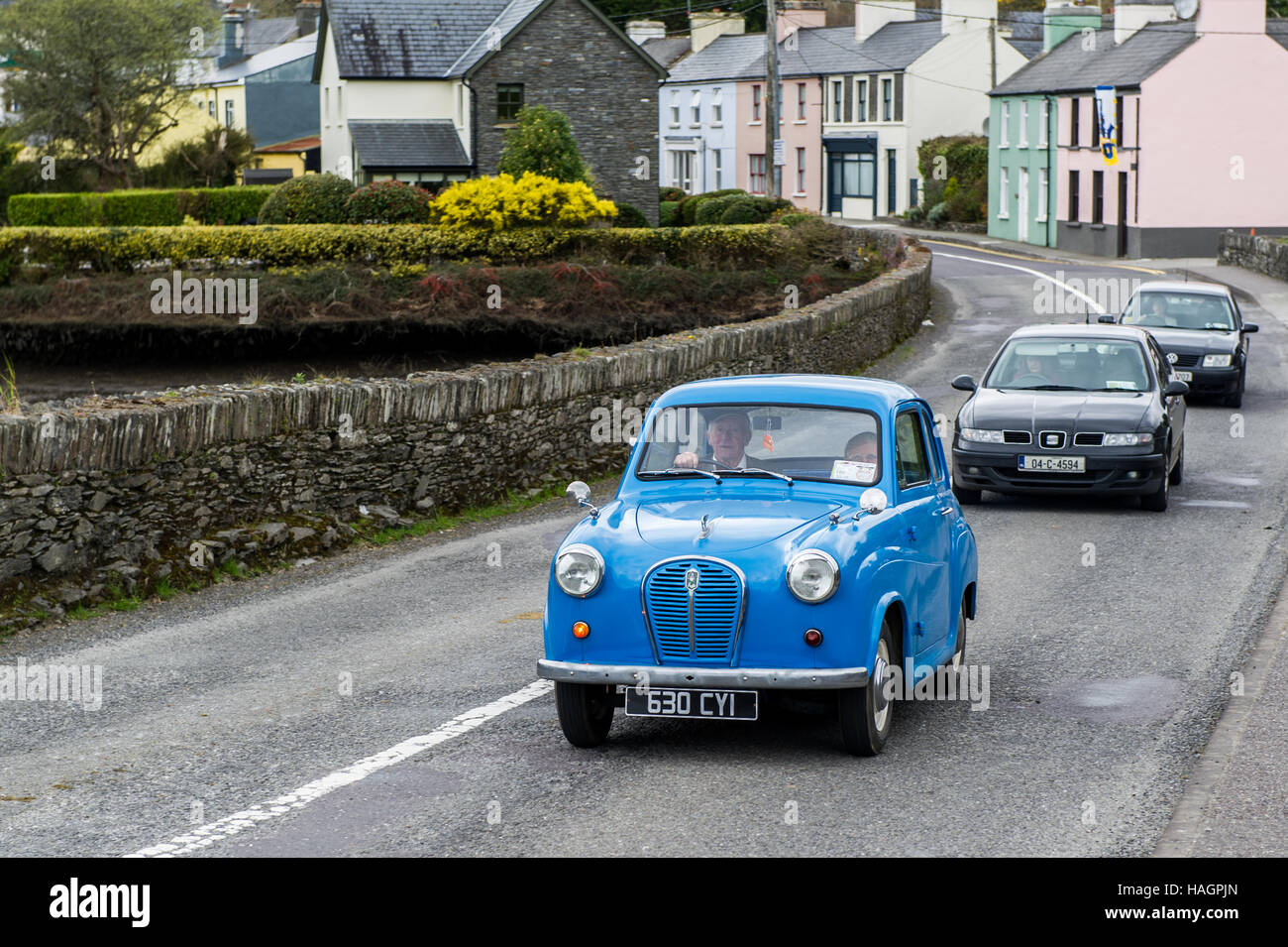 La vecchia auto blu di Austin attraversa il ponte Ballydehob, West Cork, Irlanda, seguita da auto moderne. Foto Stock