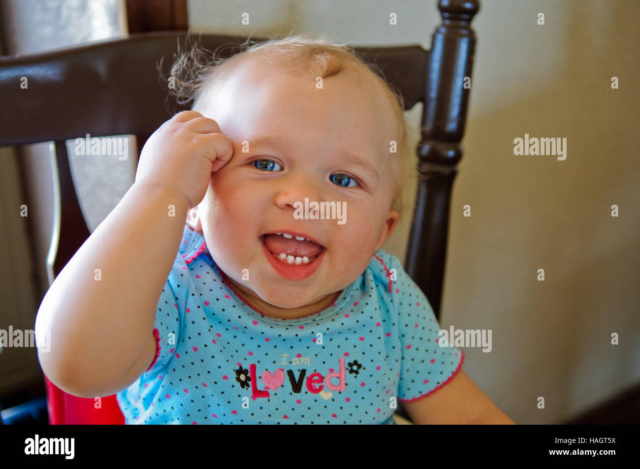 Close-up di sweet baby ragazza seduta in sede felice e sorridente. Foto Stock