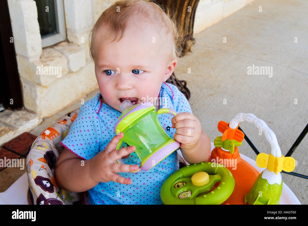 Close-up di sweet baby ragazza seduta in sede di bere sippy cup. Foto Stock
