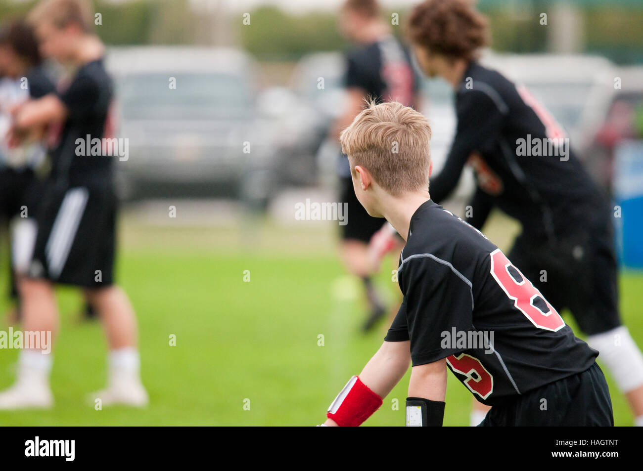 Giovane atleta giocando 7 su 7 ragazzo di calcio in nero e rosso jersey. Foto Stock