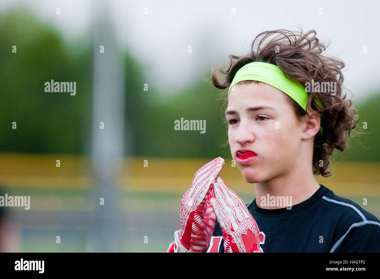 Close up di teen boy con capelli lunghi durante un 7 su 7 gioco di calcio. Foto Stock