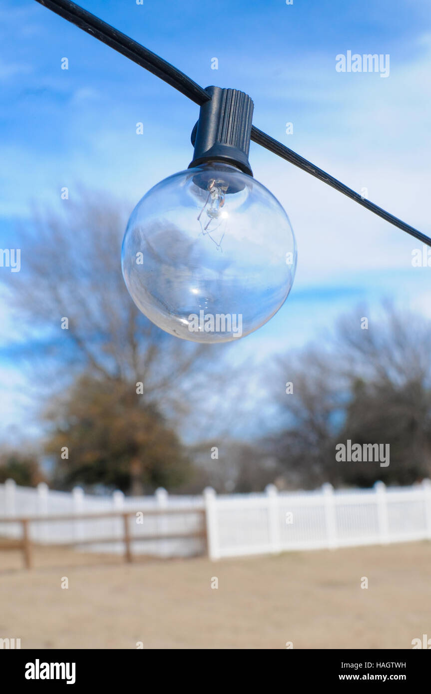 Una stringa lampadina all'aperto in cortile con recinto in background Foto Stock