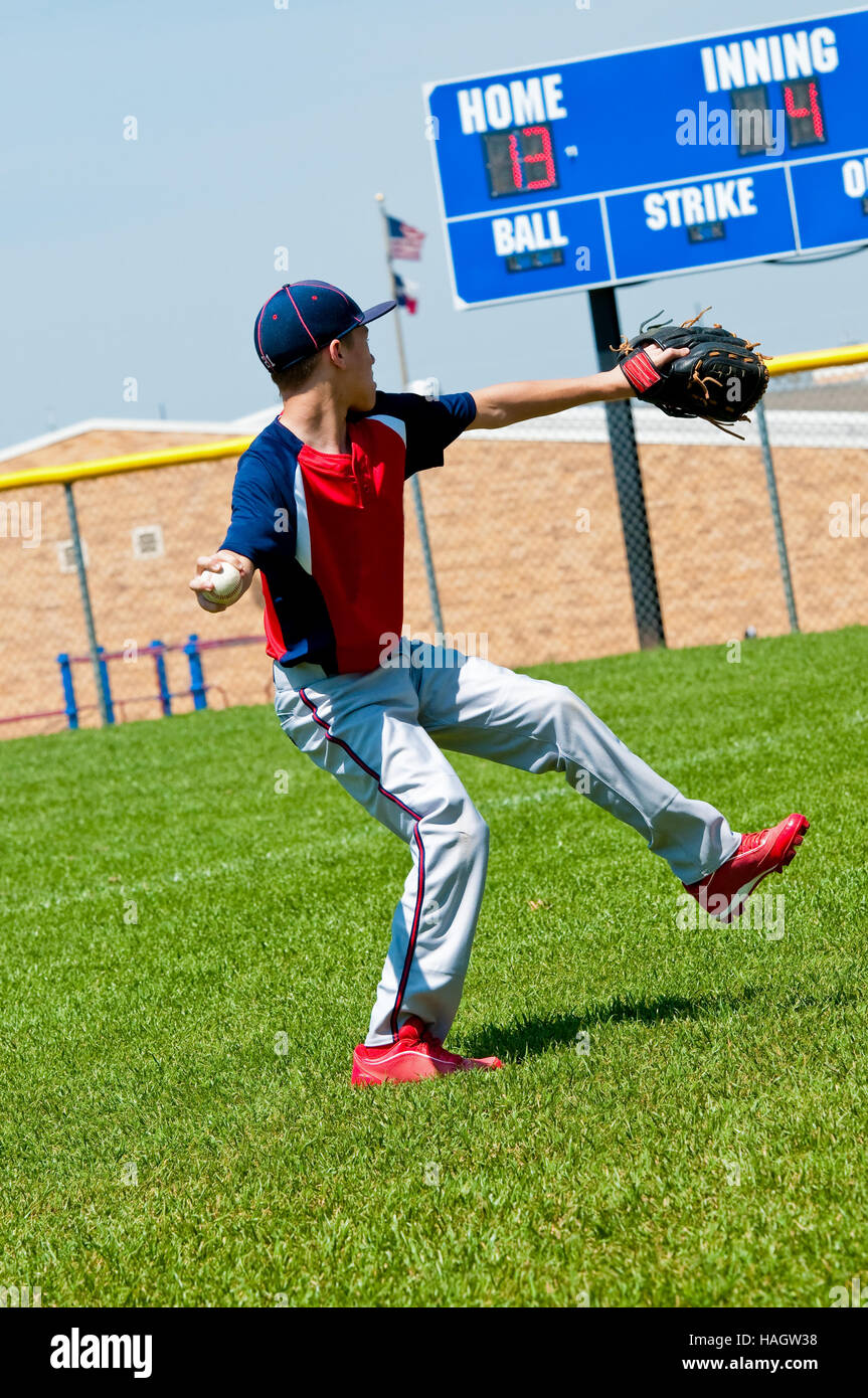 American teenage boy baseball pitching con il quadro di valutazione in background. Foto Stock