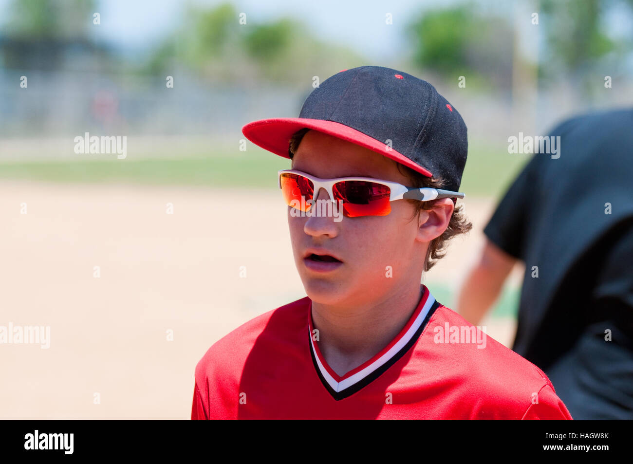La gioventù baseball ragazzo alto vicino in funzione del campo con gli occhiali da sole e cappello. Foto Stock