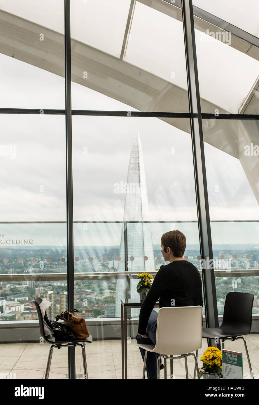 Donna seduta da sola a una tabella in un bel bar godendo la vista spettacolare del coccio dallo Sky Garden Foto Stock