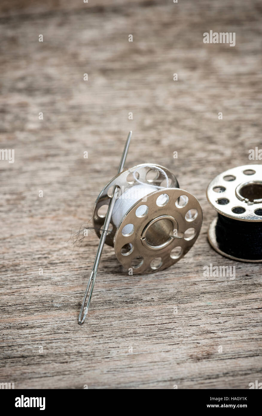 Gli steli di metallo di filo e ago di cucitura su sfondo di legno Foto Stock